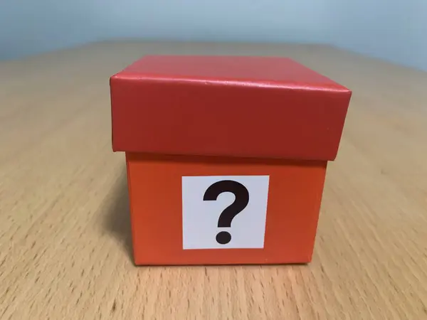 Mystery box, Small red cardboard box with a question mark printed on box, sitting in wooden table
