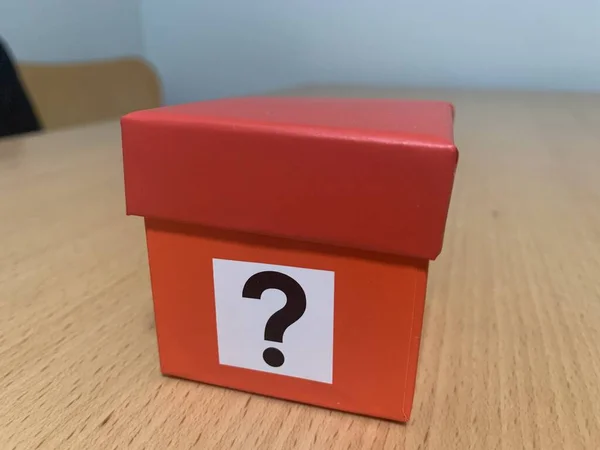 Mystery box, Small red cardboard box with a question mark printed on box, sitting in wooden table