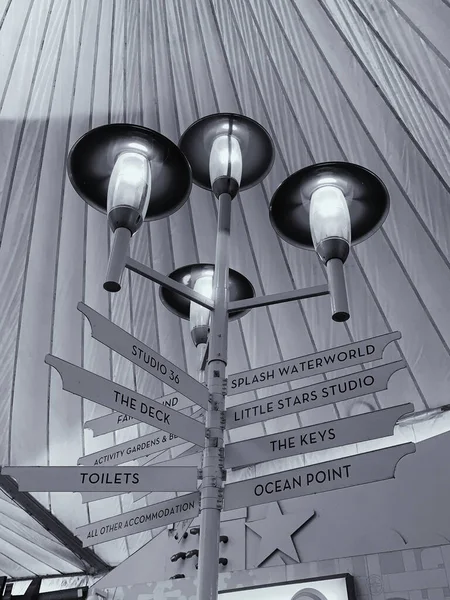 Monochrome picture of a sign post with modern light fixtures taken indoors