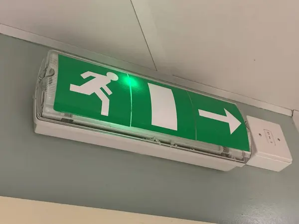 Emergency exit sign, attached to a wall above a doorway