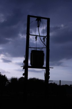 Üç aşamalı siluet 11KV üzerinde güç hattı ve direkte trafo var.