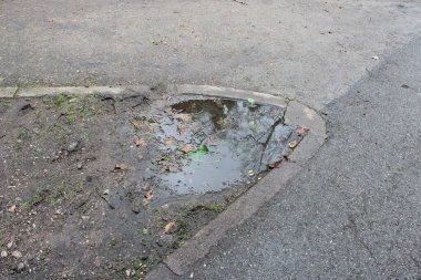 Kaldırımın kenarından çekilen su birikintisi, bulutlu bir kış gününde çekilen fotoğraf.