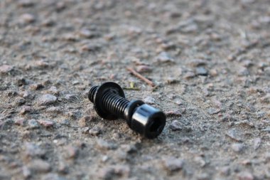 Beton yolda duran siyah cıvata.