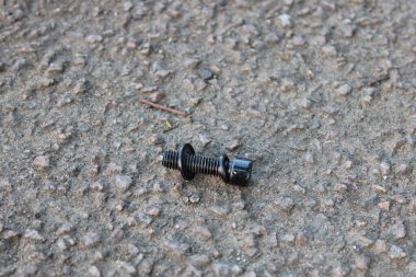 Beton yolda duran siyah cıvata.