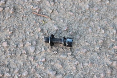 Beton yolda duran siyah cıvata.