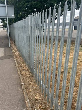 Arka planda Ağaclı Şehir Kaldırımı Boyunca Metal Güvenlik Çiti