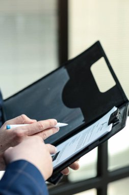 Resmi bir iş elbisesi giyen bir adam, profesyonel bir iş ya da anlaşma tasvir eden belgeleri imzalarken yakalandı.