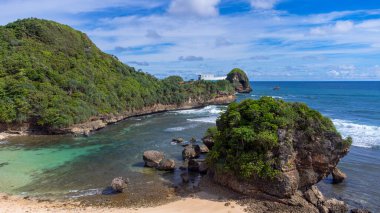 Watu Leter Plajı 'nda mavi ve bulutlu bir gökyüzünün olduğu çok güzel bir manzara.