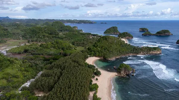 Watu Leter Plajı Tropikal Ormanı uzun kıyı şeridiyle uzaktan görülebilir.