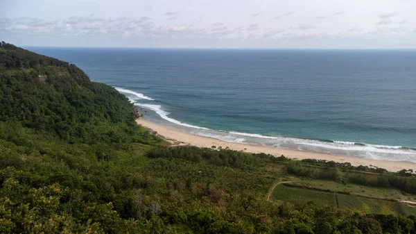 Mondangan Sahili 'nin bir tarafı mavi ve yeşil deniz renkleriyle, beyaz kumla ve tropikal ormanların yakınında görülebilir.