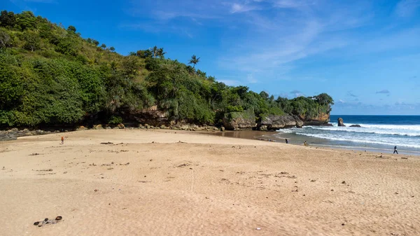 Ungapan Sahili 'nde beyaz kumlar ve kayalıklarda bir sürü yeşil ağaç ve çok büyük dalgalar.