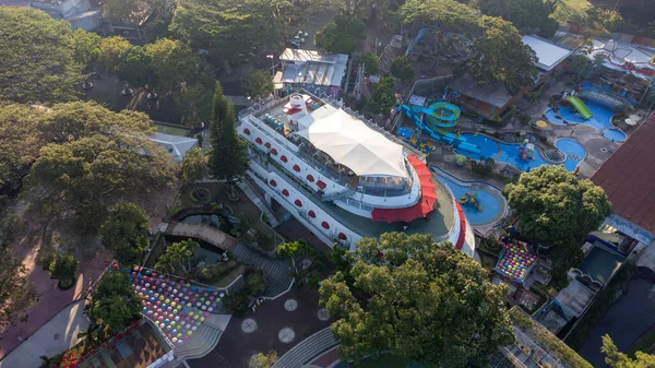 Ağaçlar ve ortasında büyük bir tekne olan bir yüzme havuzu var.