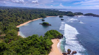 Gündüz çekilmiş Kondang Merak Sahili 'nin havadan görünüşü, masmavi bir gökyüzü ve koyu mavi deniz suyuna ışık efekti veriyor..