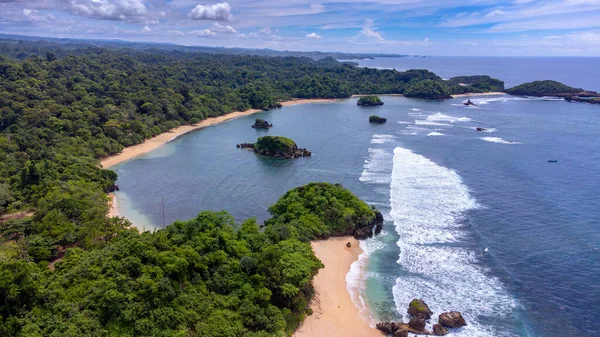 Gündüz çekilmiş Kondang Merak Sahili 'nin havadan görünüşü, masmavi bir gökyüzü ve koyu mavi deniz suyuna ışık efekti veriyor..