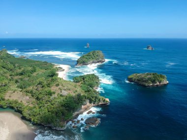 Ungapan Sahili Doğu Java, Endonezya 'da, ormanlara ve mavi deniz suyuna yansıyan gölge ışınlarıyla dolu.