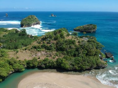 Ungapan Sahili Doğu Java, Endonezya 'da, ormanlara ve mavi deniz suyuna yansıyan gölge ışınlarıyla dolu.