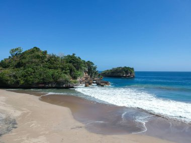 Ungapan Sahili Doğu Java, Endonezya 'da, kumsal kumları, dalgalar ve tepeler ve uçurumların manzarası.