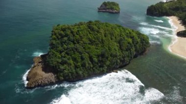 Tanjung Penyu Plajı 'nda tropikal ağaçlarla kaplı küçük bir adanın yörüngesel hava manzarası