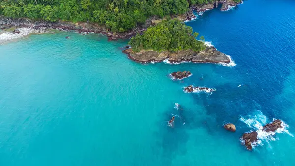 Turkuaz suları ve Lenggoksono Sahili 'ndeki kayalık kıyı şeridi olan tropikal bir adanın havadan görünüşü.