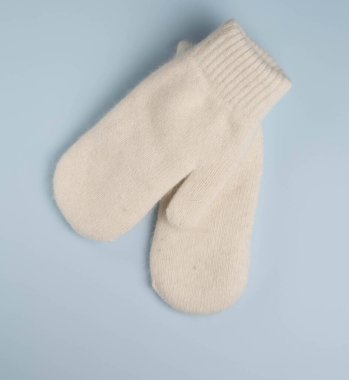 Mavi arka planda sıcak beyaz kış eldivenleri. Üst manzara, düz uzanma.