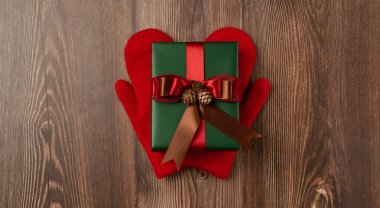 Kırmızı eldivenli kırmızı kurdeleli Noel hediyesi kutusu. Üst görünüm
