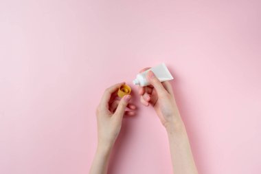Pastel pembe arka planda kadın el test kremi.