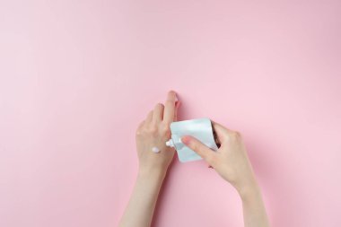 Pastel pembe arka planda kadın el test kremi.