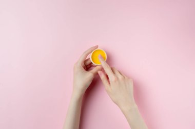 Pastel pembe arka planda kadın el test kremi.