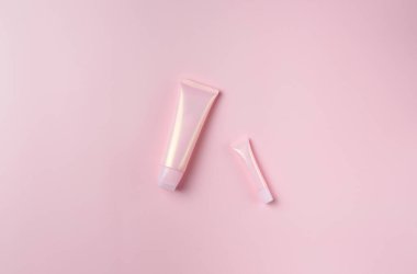 Pastel pembe arka planda iki pembe tüp, üst manzara.