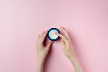 Pastel pembe arka planda kadın el test kremi.