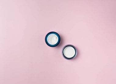 Krema kavanozu pembe arka planda izole edilmiş, üst görünümde.