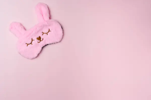 Pink sleeping mask on a pastel pink background