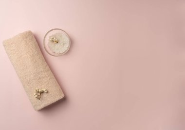 Pastel pembe arka planda deniz tuzu ile havlu. Spa konsepti