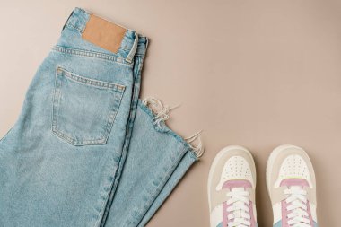 Bej arka planda kadın kotu ve spor ayakkabısı.