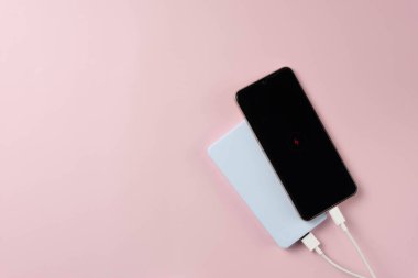 Pembe arka planda güç bankası ve akıllı telefon.