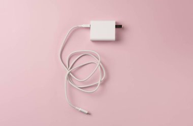 Pembe arka planda cep telefonu şarjı.