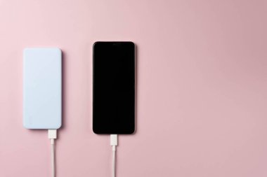 Pembe arka planda güç bankası ve akıllı telefon.
