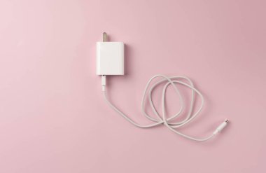 Pembe arka planda cep telefonu şarjı.