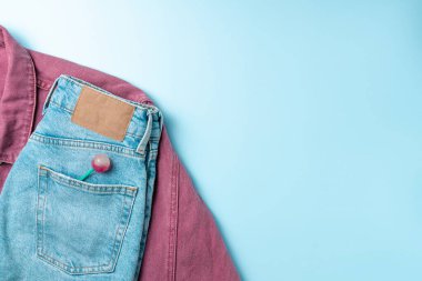 Mavi arka planda kot pantolonlu pembe kot ceket. Moda konsepti. Düz yatış, üst görünüm