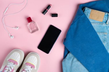 Pembe arka planda kozmetik ürünleri. Gündelik sokak tarzı, üst bakış açısı, düz yatış.