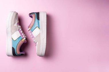 Pembe arka planda renkli ayakkabılar. Düz yatış, üst görünüm