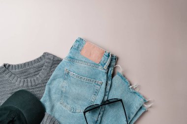 Kadın kıyafetleri ve aksesuarları bej arka planda spor tarzında. Üst görünüm