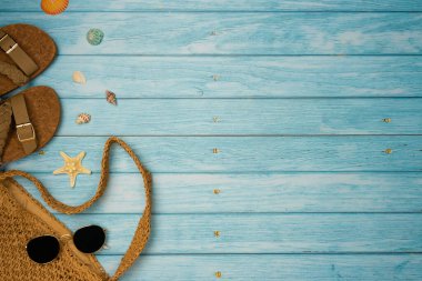 Terlikler, çanta ve mavi ahşap kaplama kabuklu güneş gözlükleri. Yaz tatilleri, plaj aksesuarları. Üst görünüm, alanı kopyala