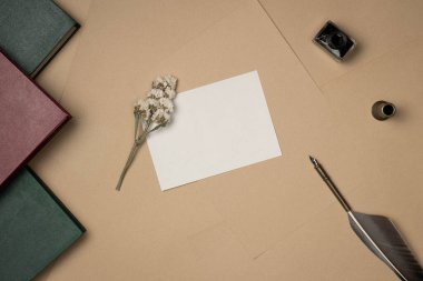 Tükenmez kalem, mürekkep, kitap ve çiçeklerle dolu boş kağıt listesi yukarıdan geliyor. Eski model. Boşluğu kopyala