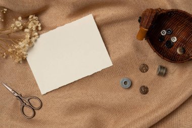 Yukarıdan bir kumaş zemin üzerinde makas ve düğme ile boş kağıt liste. Boşluğu kopyala