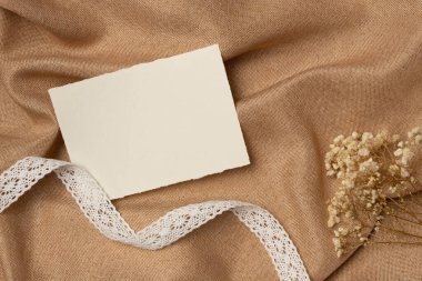 Kurdeleli ve çiçekli boş kağıt listesi yukarıdan kumaş arka planda. Boşluğu kopyala