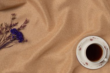 Kumaş arka planında çiçek olan bir fincan kahve. Eski tarz. Boşluğu kopyala