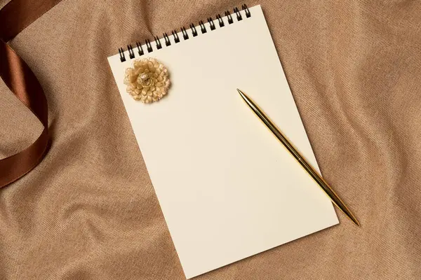Yukarıdan gelen bir kumaş arka planında kalem olan boş bir defter. Boşluğu kopyala