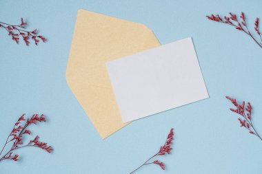 Yukarıdan mavi arka planda çiçek çerçeveli beyaz kağıt listesi. Düz yatış, üst görünüm