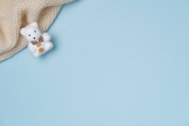 Mavi arka planda örülmüş bir eşarp takan oyuncak ayı. Boşluğu kopyala